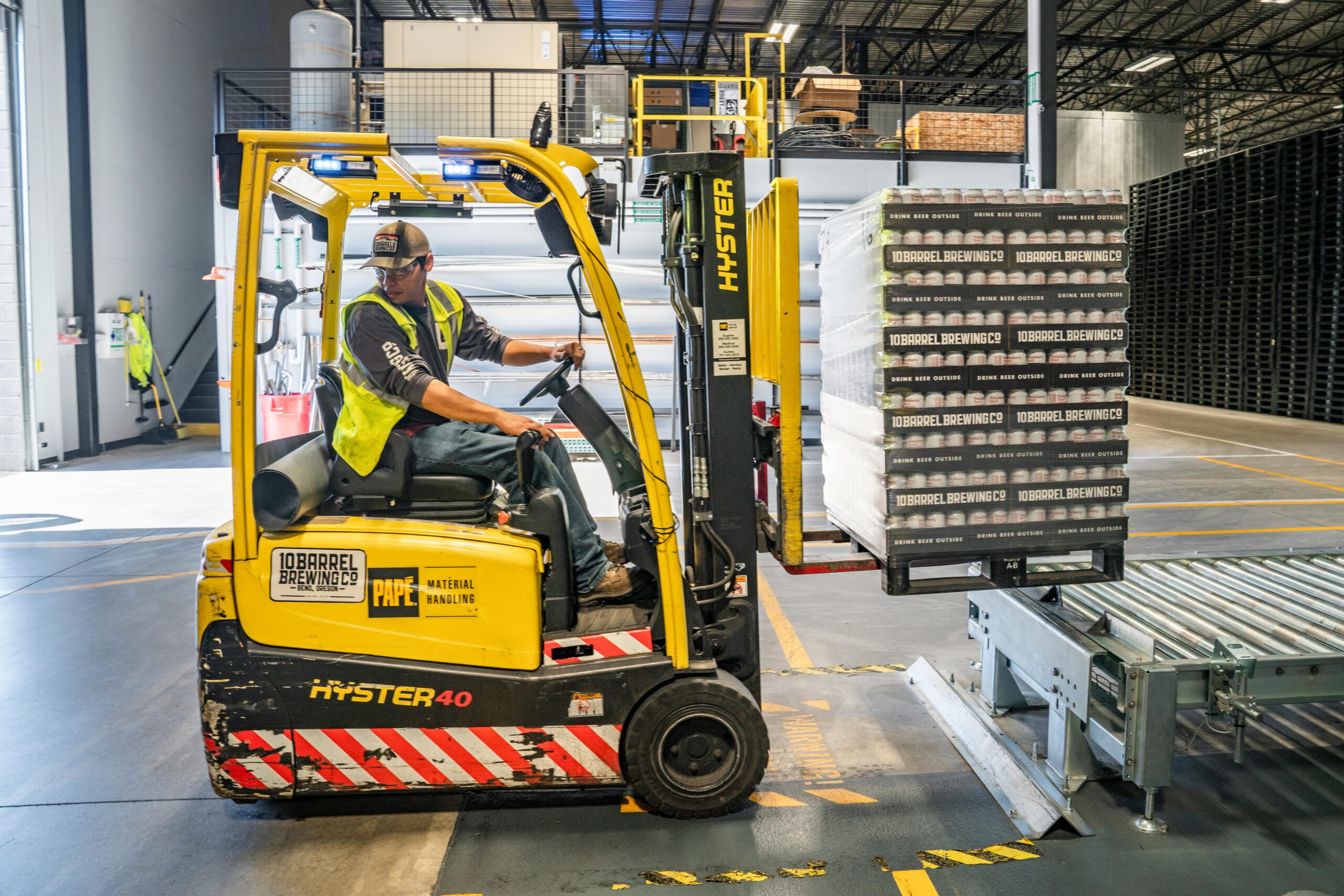 Warehouse worker operating a forklift loaded with a pallet of goods